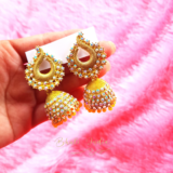 Traditional Indian jhumkas with intricate filigree work and delicate hanging pearls in yellow shade